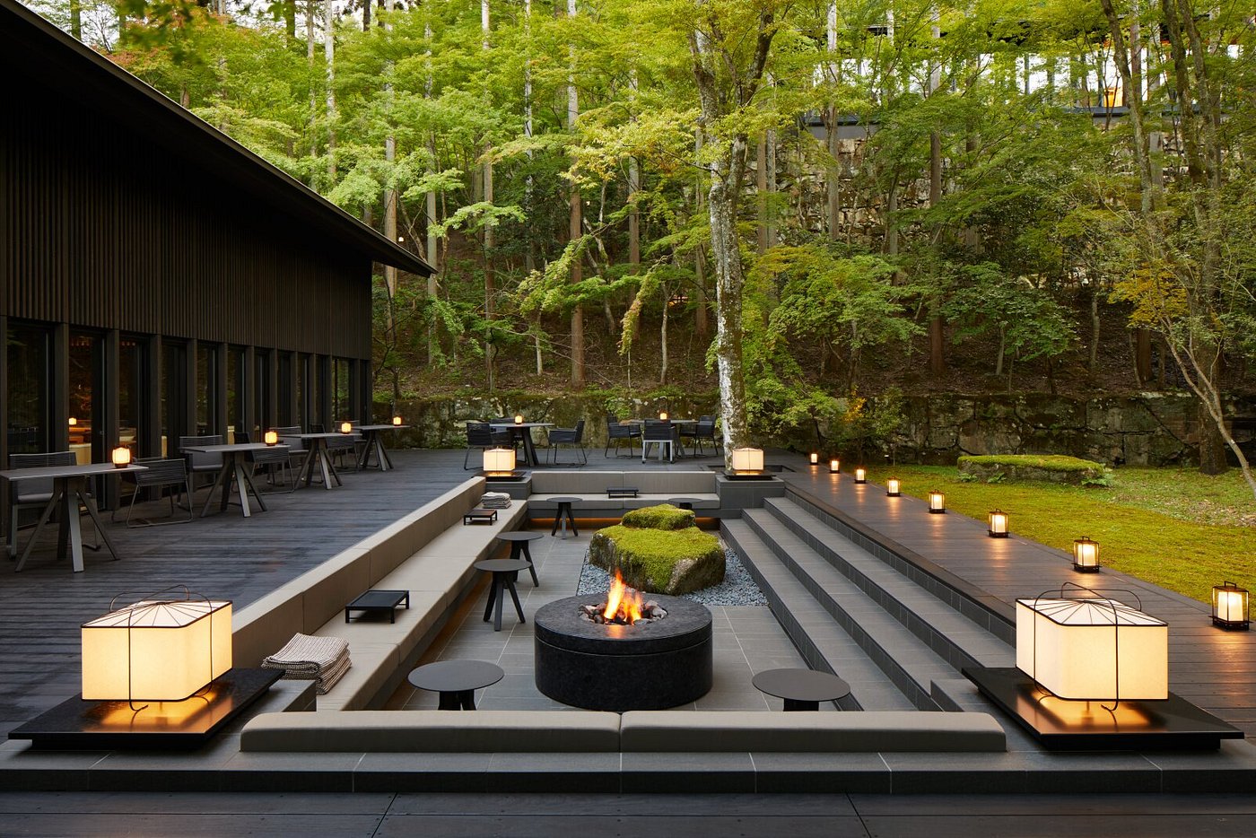 A serene view of Aman Kyoto featuring minimalist wooden architecture surrounded by lush forest and moss gardens in Kyoto, Japan