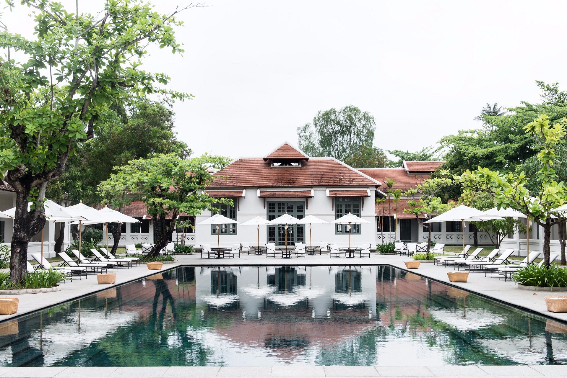 Amantaka resort in Luang Prabang with serene colonial architecture, palm-lined courtyard, and tranquil luxury ambiance